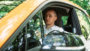 man in white dress shirt and black necktie driving car